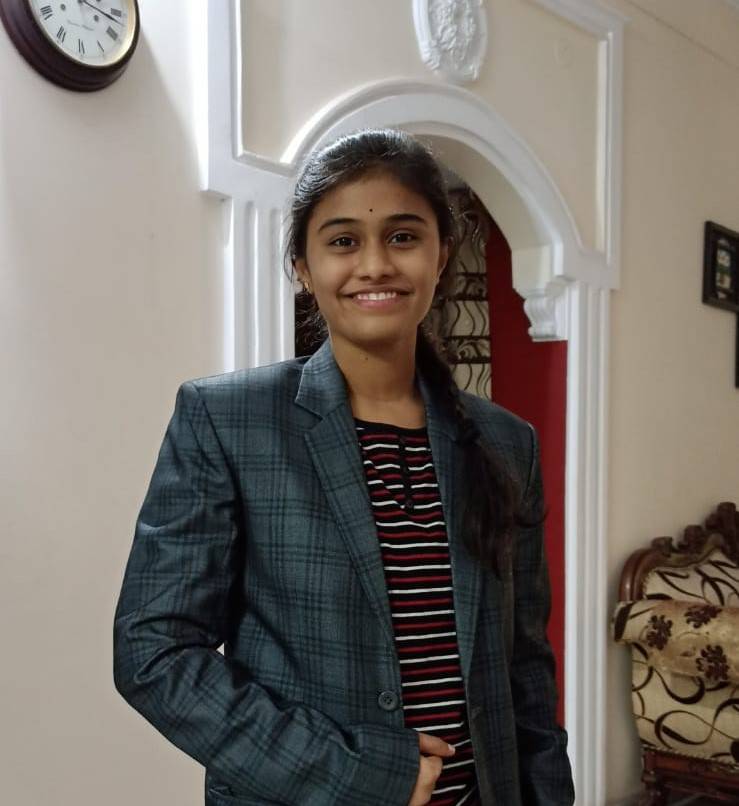 Student with brown hair smiling at the camera wearing a suit jacket